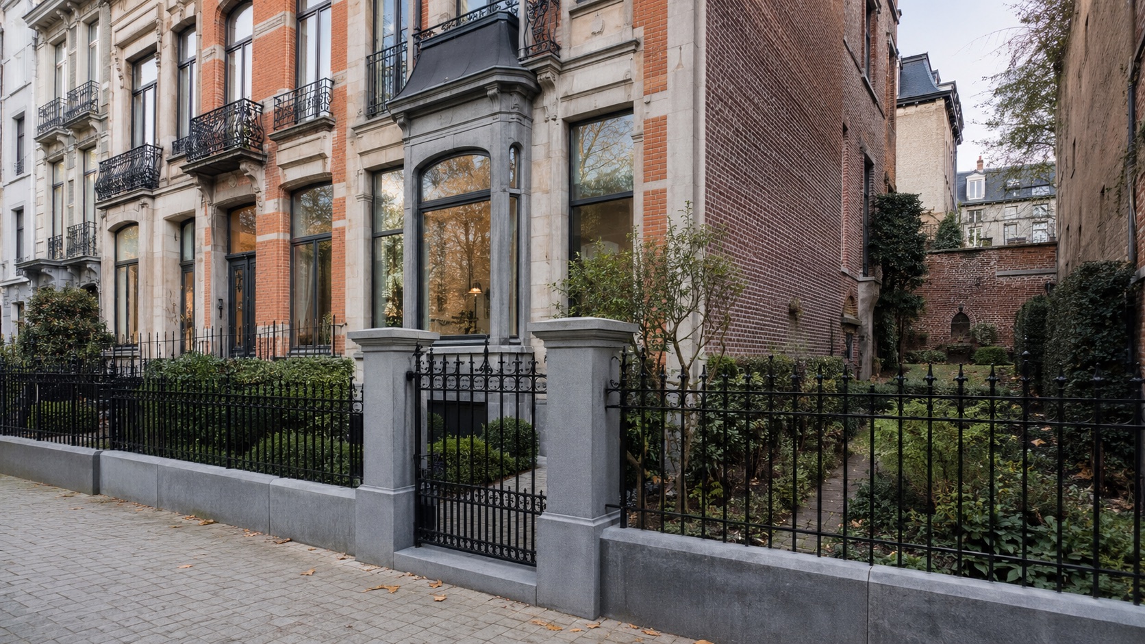 Clôture en fer forgé et muret en pierre bleue devant des maisons bruxelloises